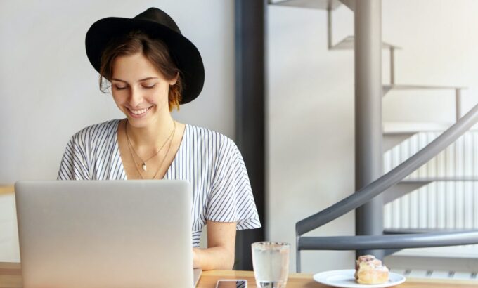 pretty-young-female-copywriter-wearing-black-hat-and-stripped-blouse-working-on-laptop-computer-loo.jpg